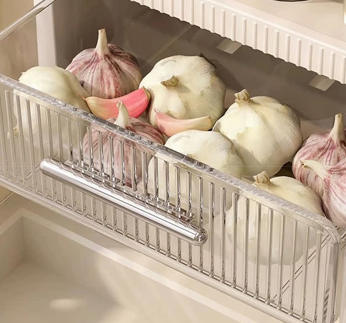투명한 서랍을 앞으로 당겨 연 모습으로, 서랍 안에 마늘이 가득 담겨 있고 은색 손잡이가 서랍 앞면에 달려 있다
