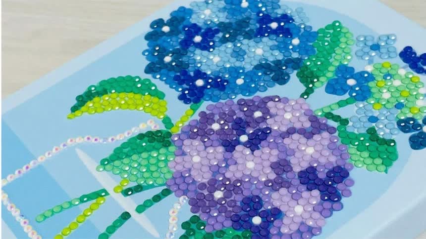 비즈를 모두 붙인 수국 도안의 파랑·보라 꽃송이와 초록 잎, 병 모양 윤곽을 가까이서 본 모습